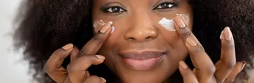 Young woman rubbing moisturizer or lotion under her eyes