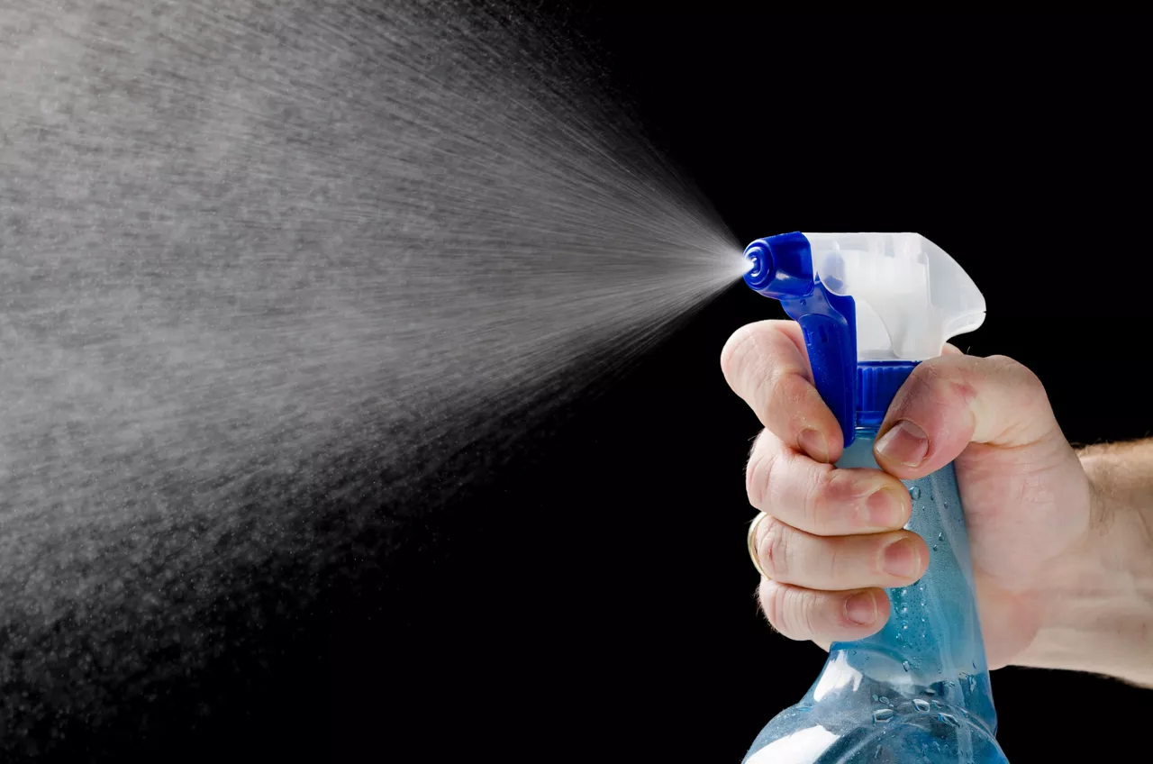 spraying liquid cleaner on black background