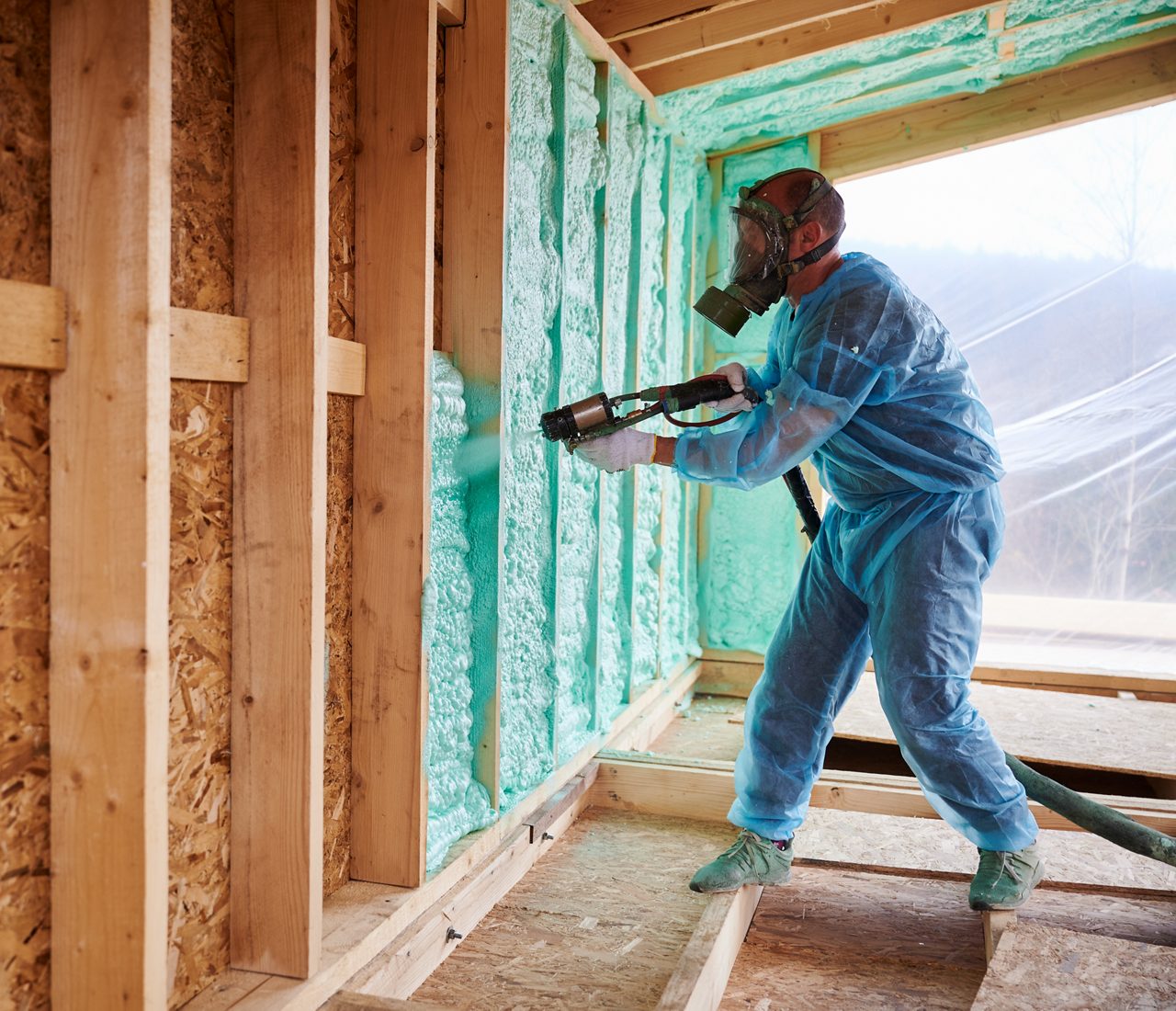 Male worker spraying polyurethane foam inside of home