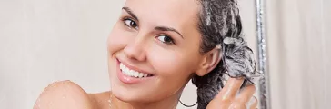 Young woman washing her head in the shower by shampoo