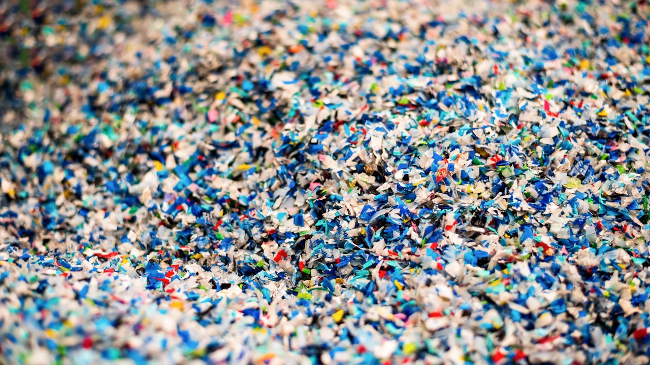 Close view of the multicoloured shredded plastic garbage at waste recycling factory