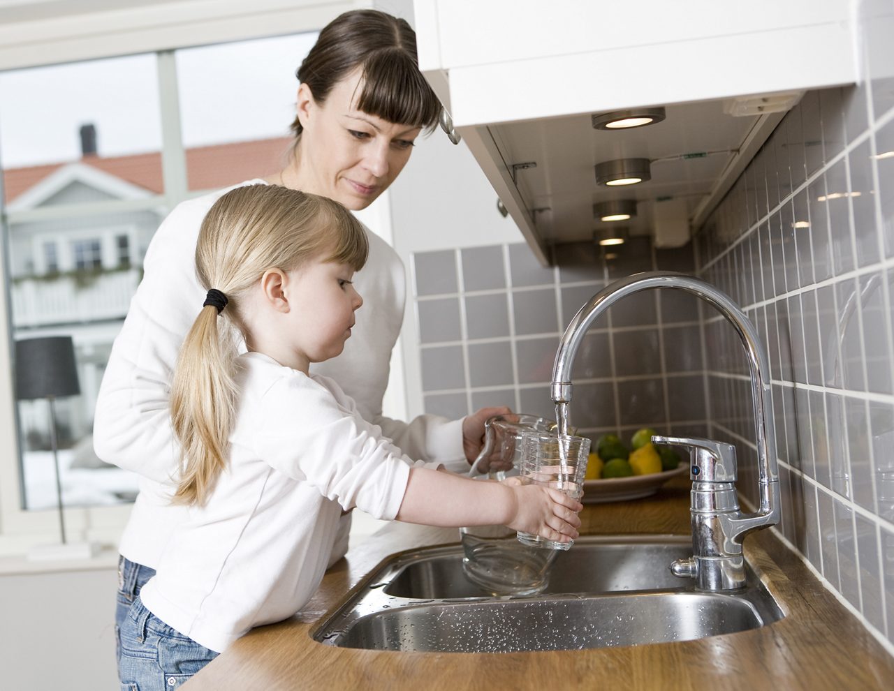 Girl in the kitchen with her mother getting a glass of water