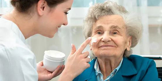 Nurse assists an elderly woman with skin care and hygiene measures at home
