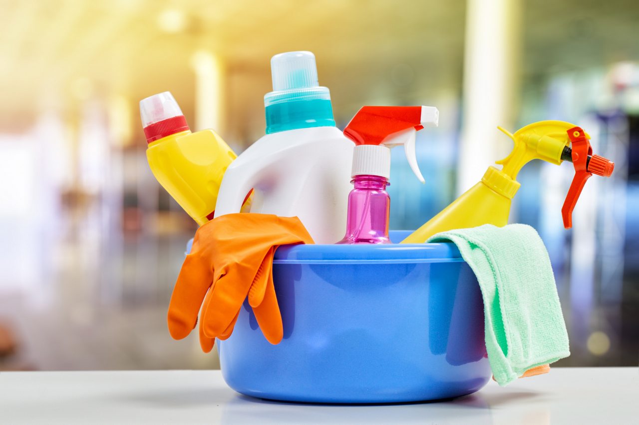 Close up of plastic tub filled with various cleaning supplies