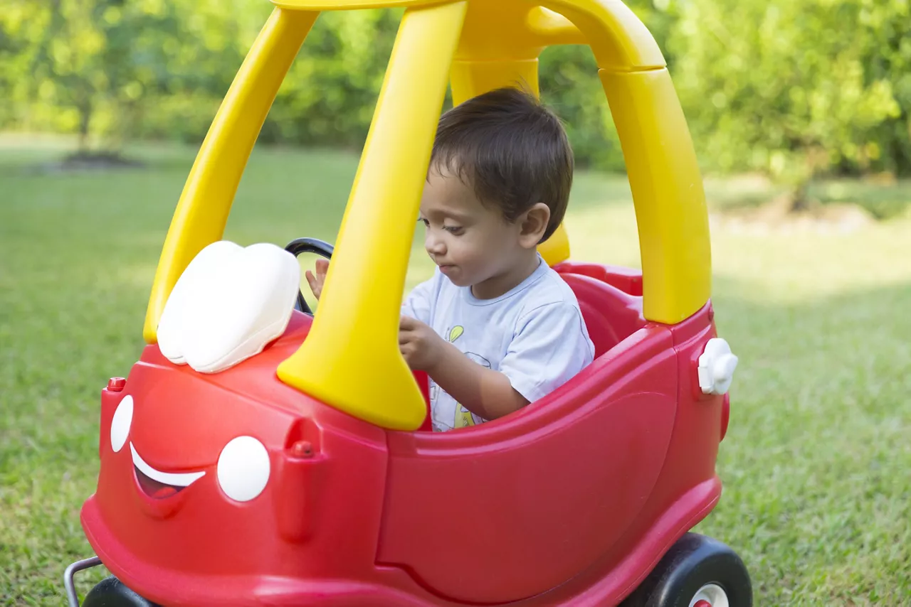 Happy Little Boy Driving His Toy In The Park