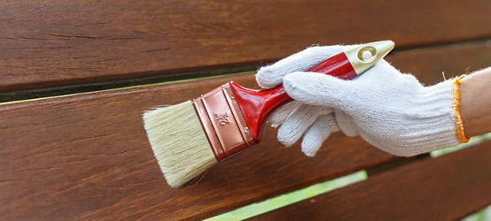 Hand holding brush and paint timber