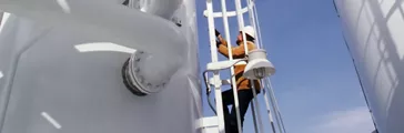Man climbing ladder at industrial plant 