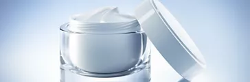 Open glass jar of cream on blank white background