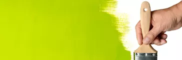 Hand using paintbrush with green Paint on wall