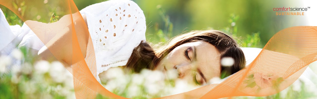 Mulher deitada com travesseiro no campo de grama, elementos de marca e logotipo da ComfortScience Sustainable 