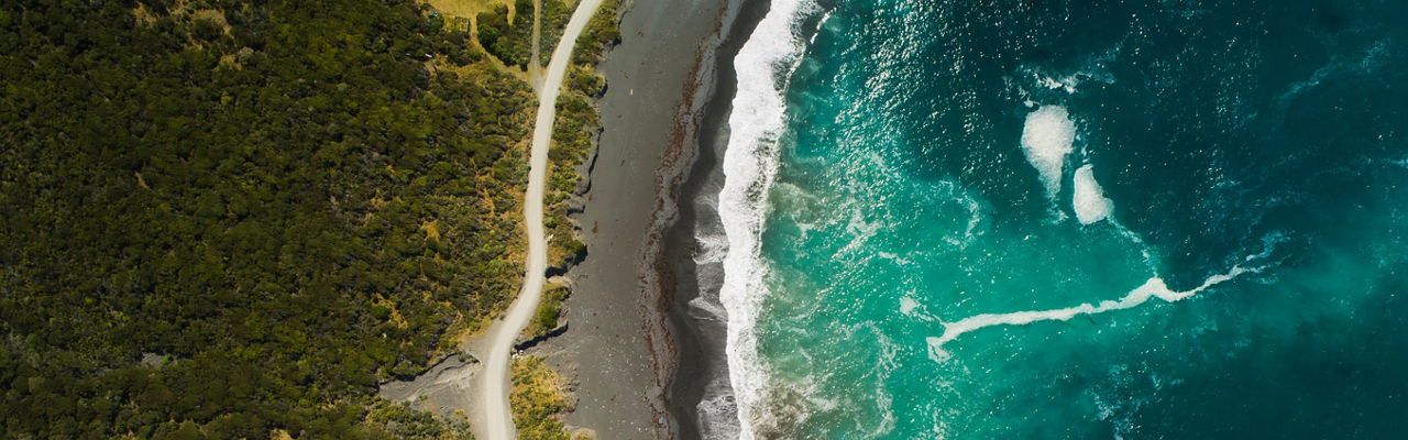 Ponto de vista do drone de uma única estrada de faixa que passa ao lado de uma costa.