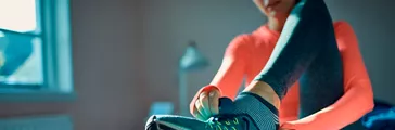 Close up of a woman putting on her athletic running shoe to workout