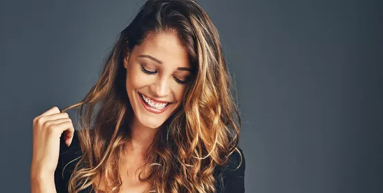 Studio shot of a beautiful woman with long locks posing against a grey background