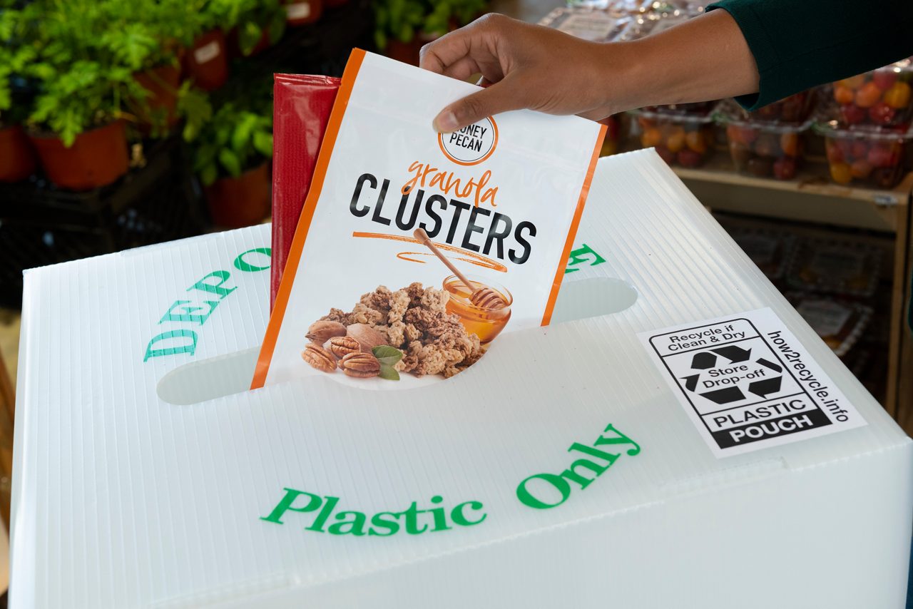 Granola Clusters plastic packaging being placed in a Plastic Only recycle bin at the grocery store.