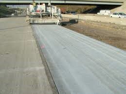 A newly constructed concrete road being poured by paving machine. 