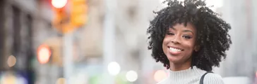 Smiling young African American woman with curly hair in the city