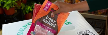 Person placing Bear Naked granola pouch in store drop-off recycling bin