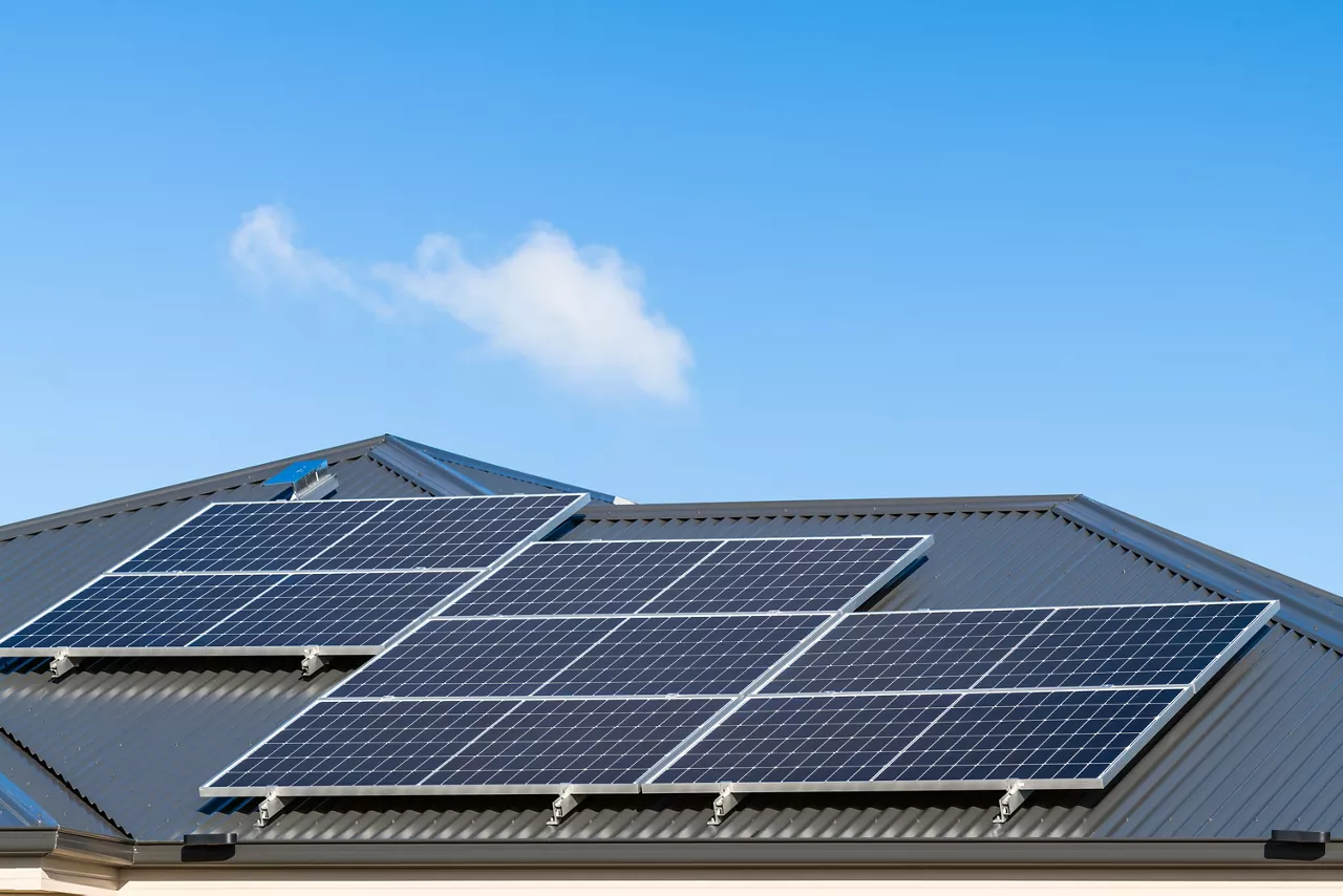 New solar panels installed on metal sheet roof of the house in South Australia against clear blue sky with small cloud