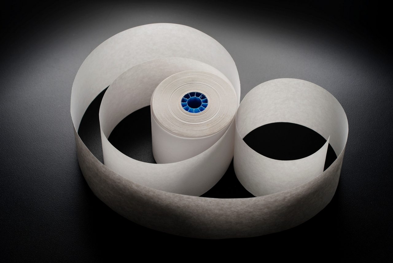 Roll of cash register paper tape on black