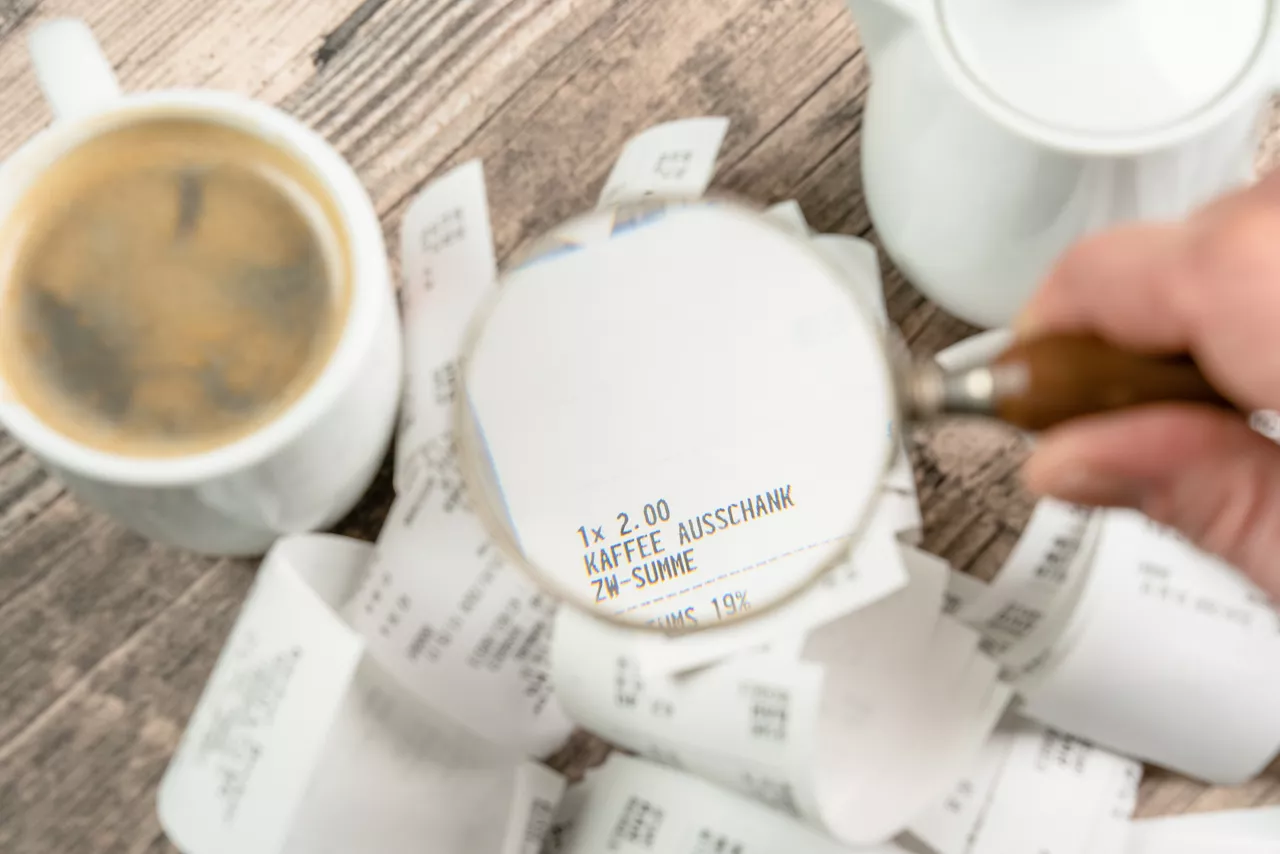 A magnifying glass enlarges a receipt on a wooden table