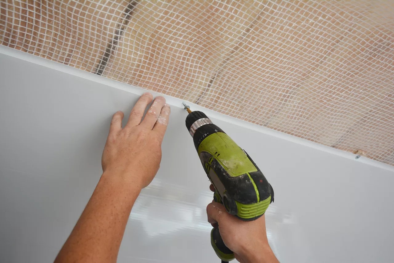 A builder is installing plastic ceiling panel