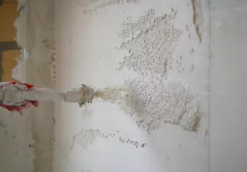 Machine application of mortar to the wall. Machine application of plaster to the wall. Plasterer throws plaster on the wall. Plastering walls in a new house.