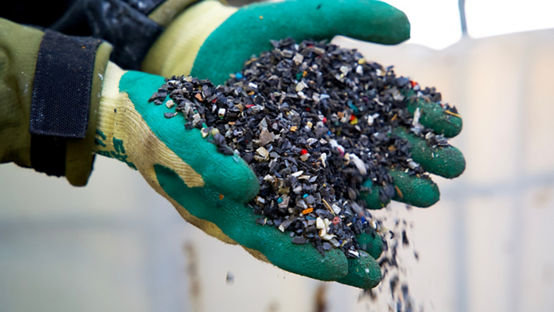 granulated plastic waste in gloved hands