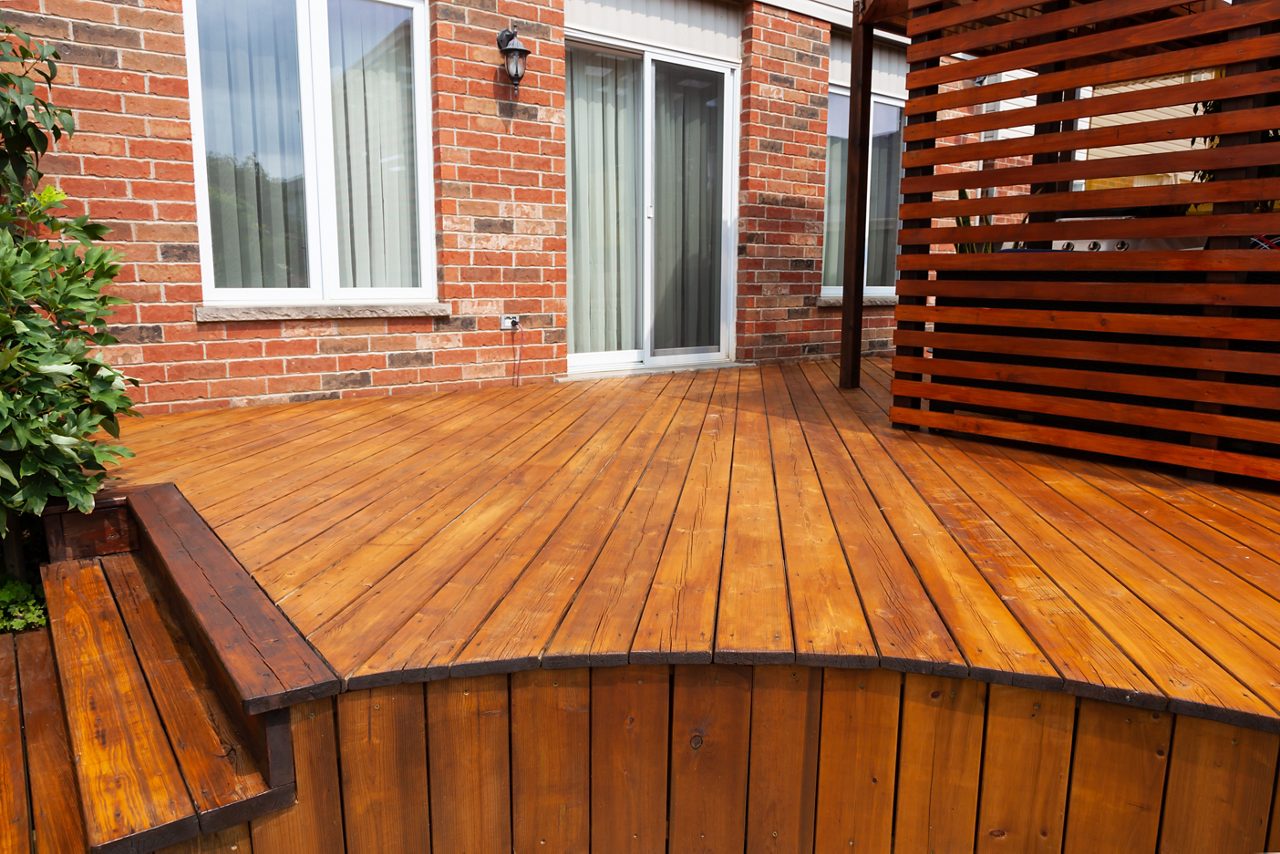 Terraza exterior de madera manchada adjunta a una casa