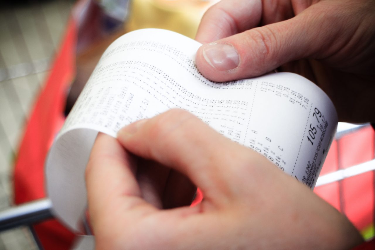 Supermarket paper check receipt bill in hand