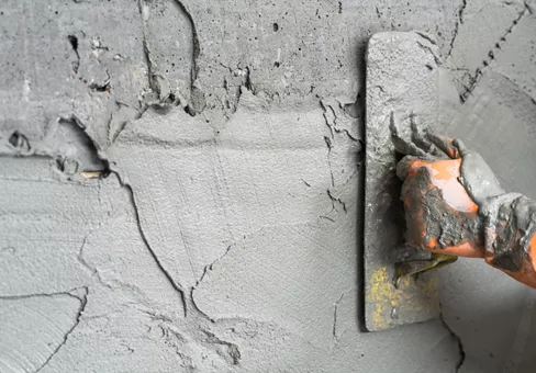 Hand worker plastering cement wall background.