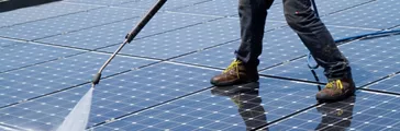 Person power washing solar panels 