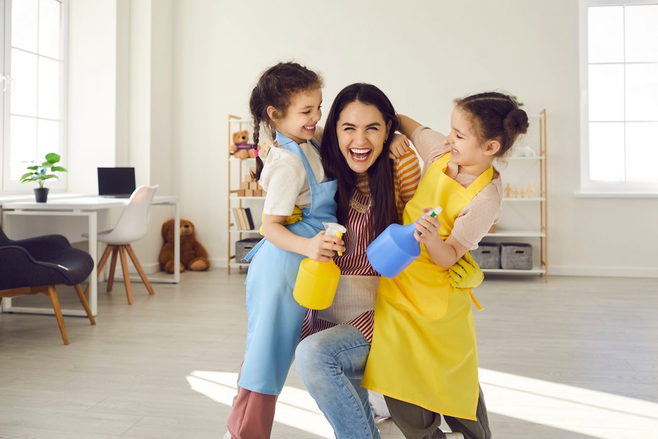 Asian mother with daughter dancing while cleaning at home