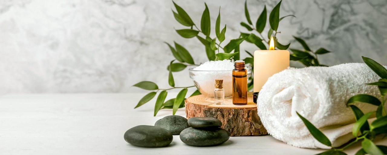 beauty treatment items for spa procedures on white wooden table. massage stones, essential oils and sea salt. copy space