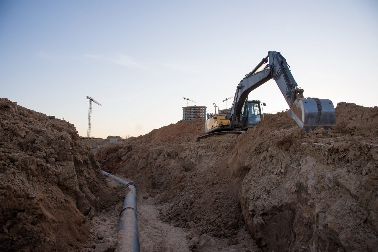 Excavator at work trenching at a construction site. Trench for laying external sewer pipes. 