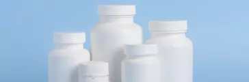 Different sizes of blank white plastic bottles of medicine pills or supplements on blue background
