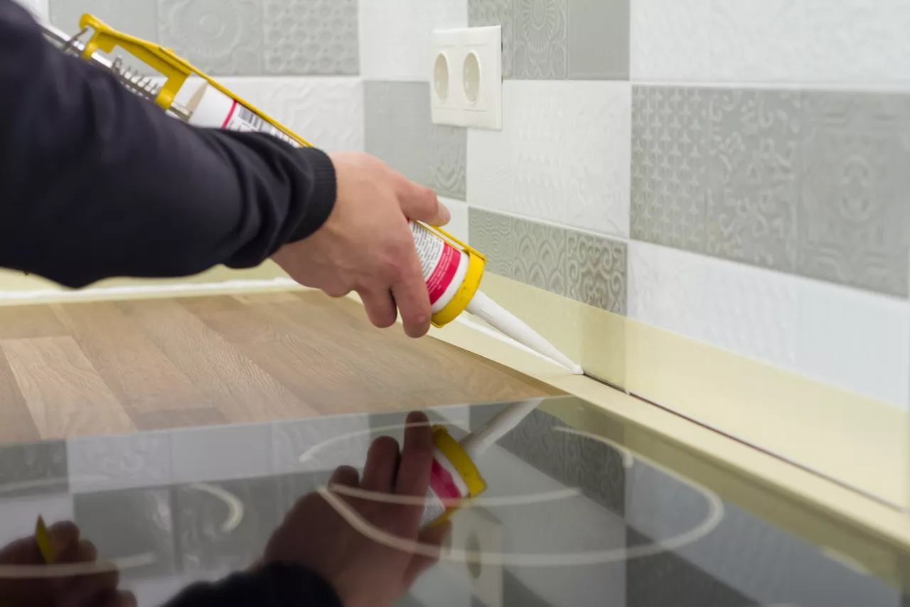 A Silicone sealant applied with construction syringe between ceramic tiles and kitchen worktop. 