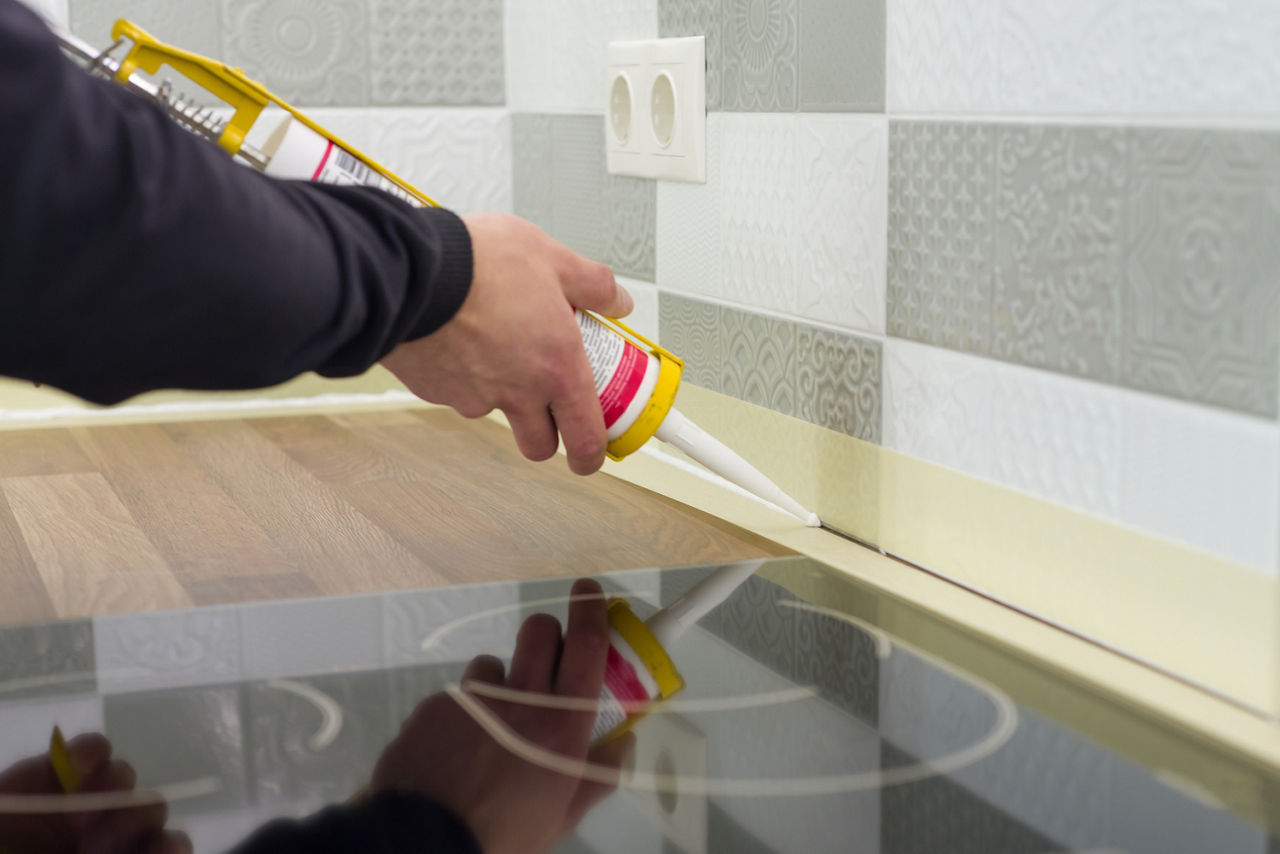 A Silicone sealant applied with construction syringe between ceramic tiles and kitchen worktop. 