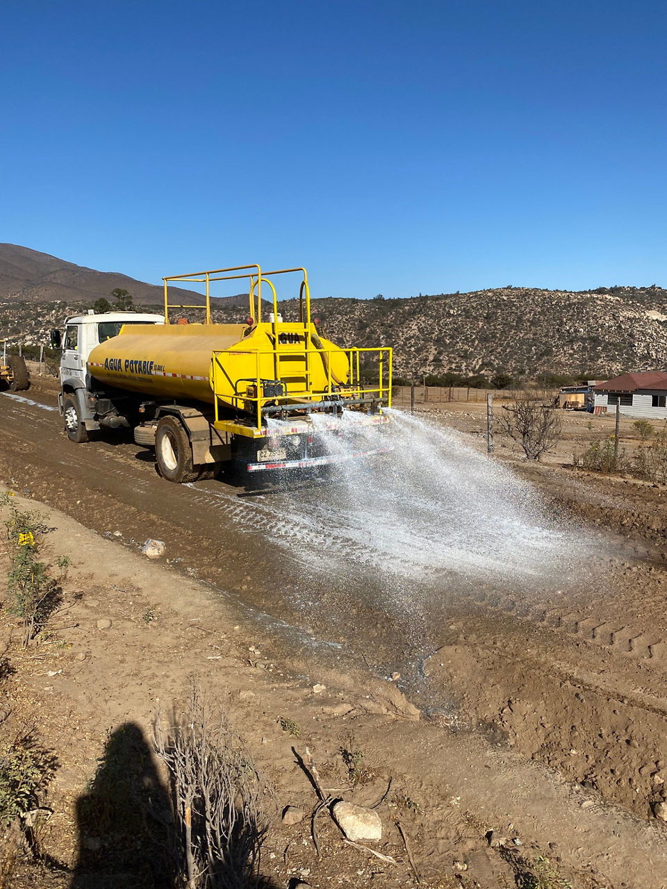 Yellow truck spraying polymer solution on dirt road
