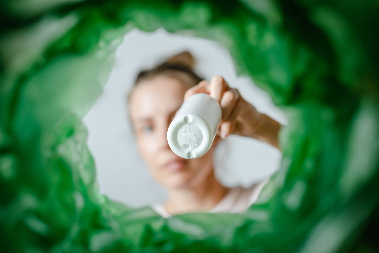 A female sorting a white package of shampoo or lotion into a bin.