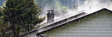 Steam comes from the roof houses when the rain falls with sunny light