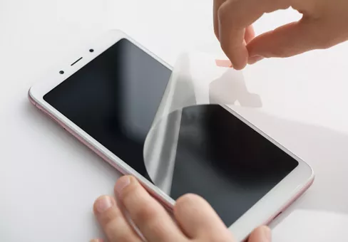 The girl's hands are removing the protective film from the screen of the smartphone.