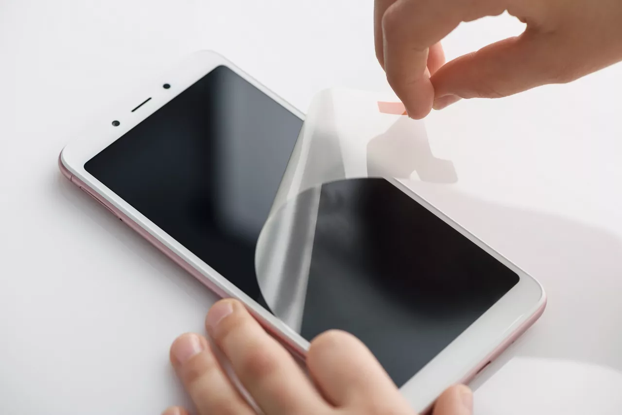 The girl's hands are removing the protective film.