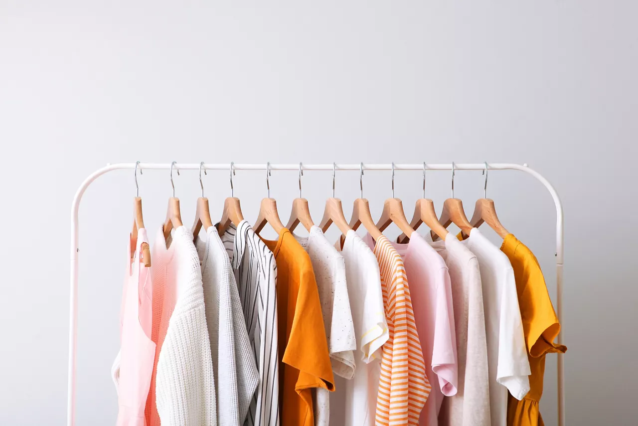  fashion clothes on a rack in a light background indoors. place for text 