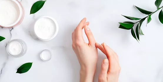 Cosmetic cream on female hands, jars with milk swirl cream.