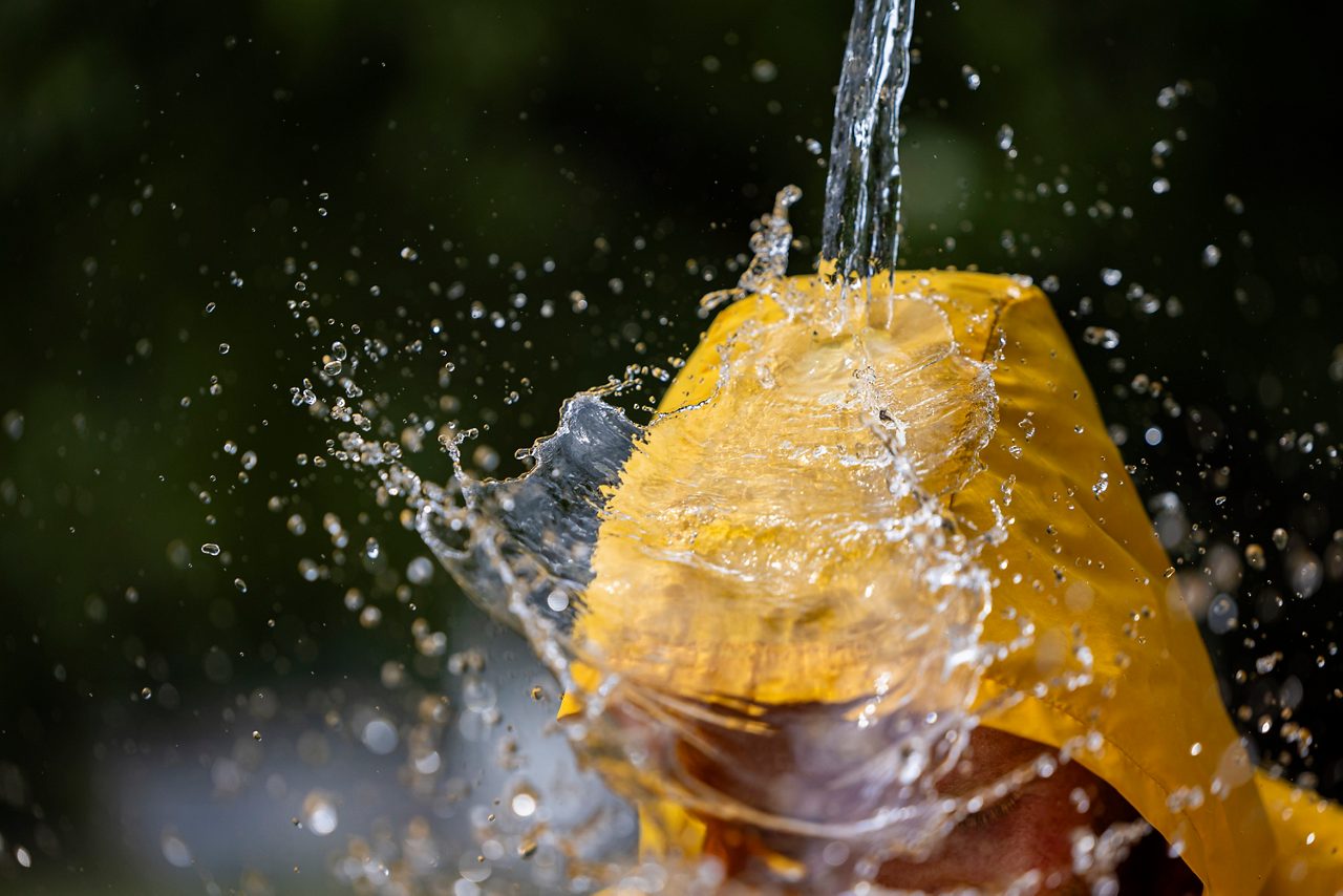 Close up of a high performance yellow rain jacket repelling water.