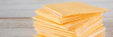 A closeup view a stack of processed cheese slices, individually wrapped in plastic.
