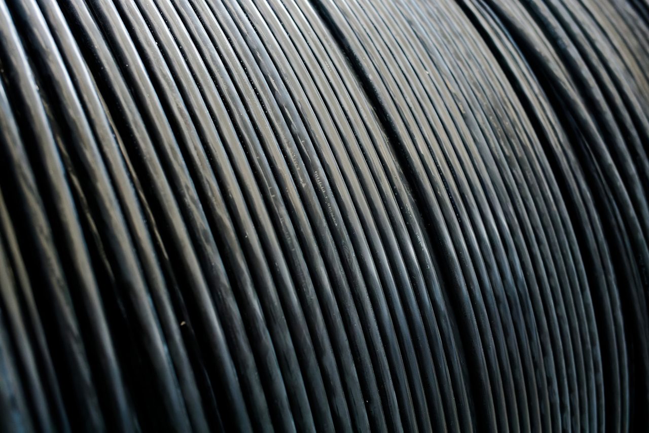 New black power cables is wound on wooden coil.