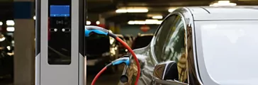 Electric car charging at a charging station in the parking garage of a shopping center