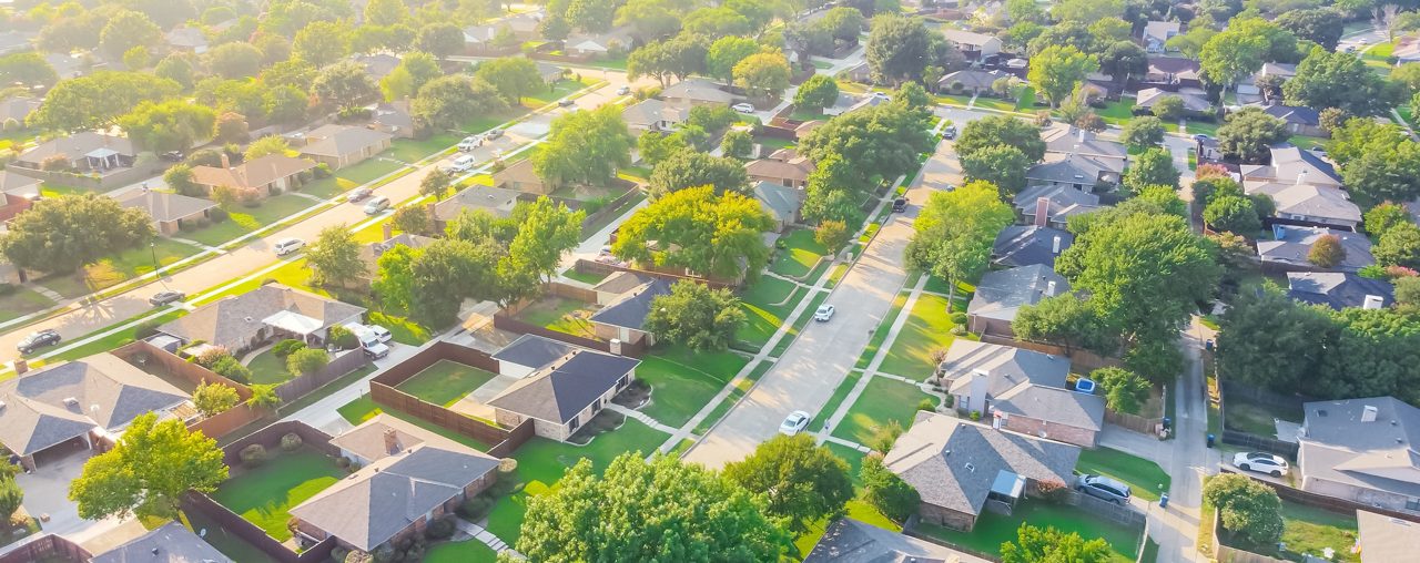 Panoramic Urban sprawl near Dallas, Texas, USA with row of single-family houses and large fenced backyard. Aerial view residential neighborhood subdivision surrounded by mature trees