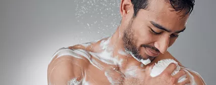 Shot of a man taking a shower against a grey background.